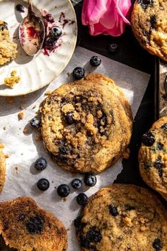 several blueberry muffins are on paper plates next to a pink flower and spoon