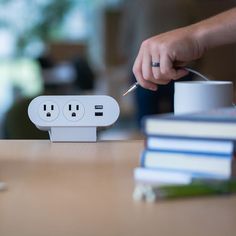 a person is plugging in to an electrical outlet on a table next to some books