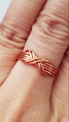 a woman's hand with a gold ring on her left hand and an arrow shaped band