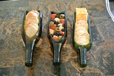 three different types of food in black plastic containers on a marble counter top, one is filled with bread and the other has olives