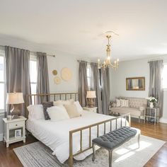 a bedroom with a bed, couch and chandelier