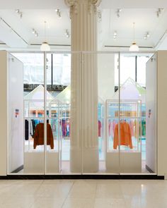 the inside of a clothing store with mannequins and clothes in glass cases