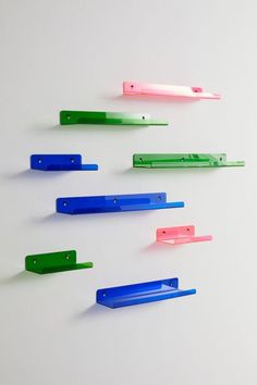 several different colored plastic objects on a white surface with one green, one pink and one blue