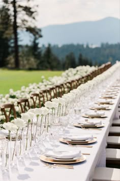 the long table is set with white flowers and place settings for guests to sit at