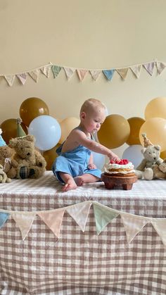 a baby sitting on a table with a cake