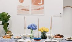 the table is set with plates and flowers in vases on it, along with other food items