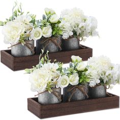 three metal vases with white flowers in them on wooden trays, tied with twine