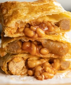 two pieces of food stacked on top of each other with beans and sausage in the middle