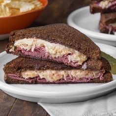 two white plates with sandwiches on them sitting on a table