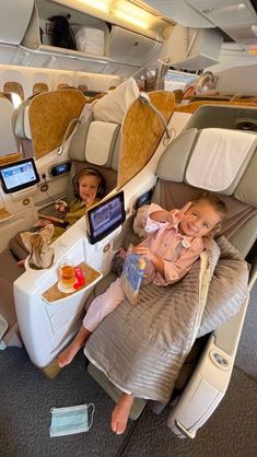 two young children sitting in an airplane seat with their laptops on the table next to them