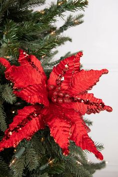 a red poinsettia ornament hanging from a christmas tree