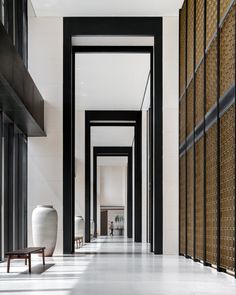 the hallway is lined with black and white walls, along with large vases on either side