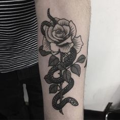 a black and white snake wrapped around a rose tattoo on the left upper half of the arm