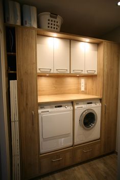 a washer and dryer in a small room with cabinets on the wall behind them