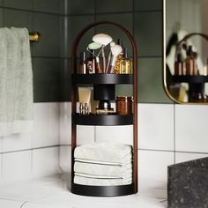 there is a shelf in the bathroom that has many items on it and some towels