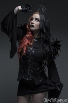 a woman with red hair and horns is posing for a photo wearing a black outfit