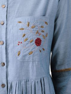 a close up of a person wearing a blue dress with gold trimmings and a rose applique on the chest