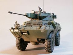 a toy army vehicle is shown on a white surface with a gray background behind it