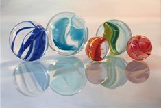 four different colored glass bowls sitting next to each other on a white surface with reflections