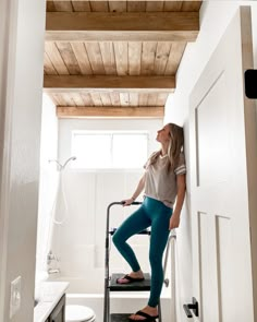 a woman standing on a ladder in a bathroom