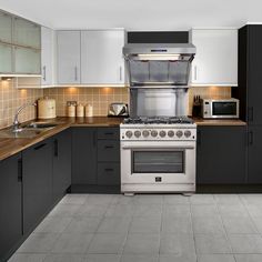 a kitchen with black and white cabinets, stainless steel stove top oven and counter tops