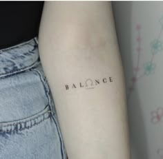 a woman's arm with the word balance tattooed on her left side ribcage