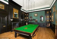 a pool table in the middle of a room with green walls and wood flooring