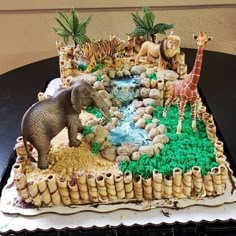 there is a cake that has animals on it and rocks in the middle with grass