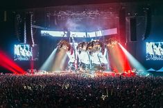 a large group of people at a concert with bright lights on the stage behind them