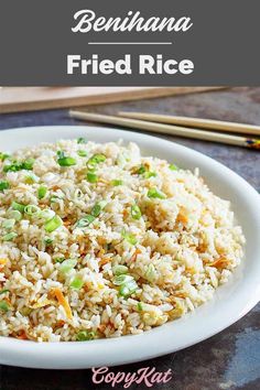 a white plate topped with rice and veggies next to chopsticks on a table