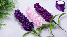 purple and white flowers are on the table next to some green leaves with a candle