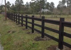 a black fence in the middle of a grassy field