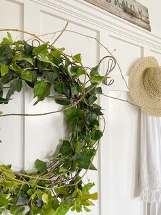 a wreath is hanging on the wall next to a straw hat and white towel with green leaves