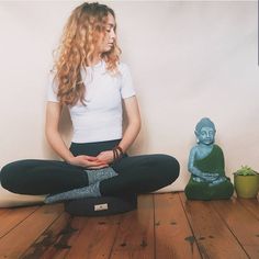 a woman sitting on the floor in front of a buddha statue