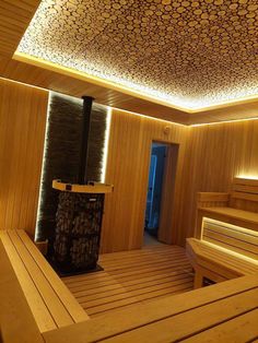 a sauna room with wooden benches and lights on the ceiling is lit by recessed lighting