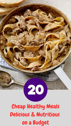 a bowl filled with pasta and meat on top of a wooden table next to bread