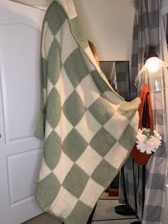 a woman standing in front of a mirror wearing a green and white checkered blanket