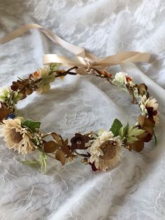 a headband with sunflowers, leaves and ribbons on a white cloth background