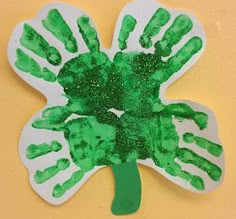 a paper plate with green handprints on it and a palm tree in the middle