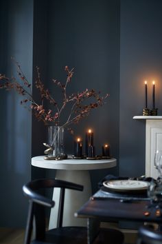 a dining room table with candles and flowers in a vase on the table next to it