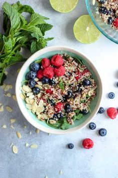 a bowl filled with granola, raspberries and blueberries next to limes