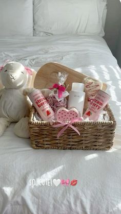 a teddy bear sitting on top of a bed next to a basket filled with personal care items