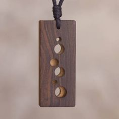 a wooden plaque with three moon phases hanging on a cord that is attached to a wall