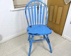 a blue wooden chair sitting in the corner of a room next to a door and window