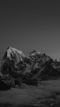 black and white photograph of mountains with clouds in foreground, stars above the top