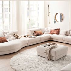 a living room filled with lots of white furniture and pillows on top of a rug