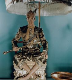 a statue sitting on top of a chair under an umbrella