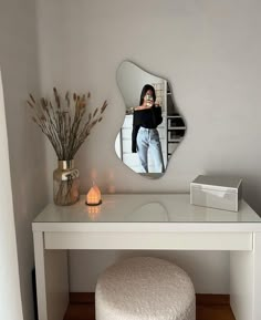 a white dressing table with a mirror on it and a stool in front of it