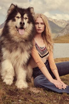 a woman sitting on the ground next to a dog