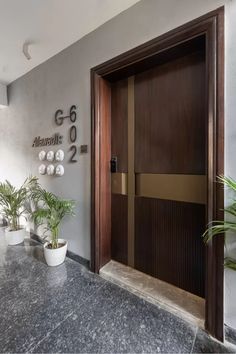 the entrance to an office building with potted plants on the counter and numbers on the wall